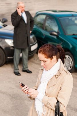 Woman and man using phones after car accident