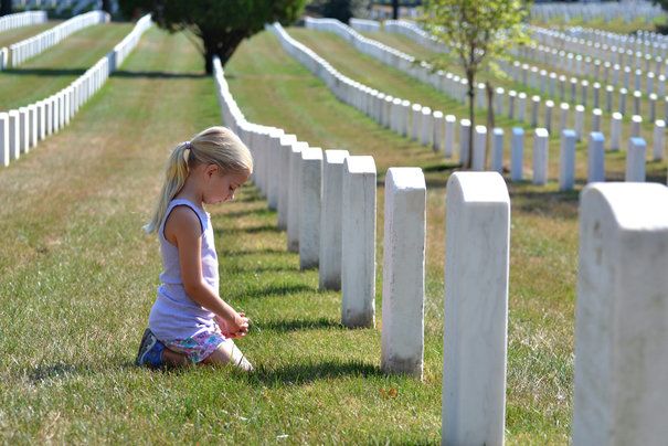 Little girl kneeling in front of white gravestones