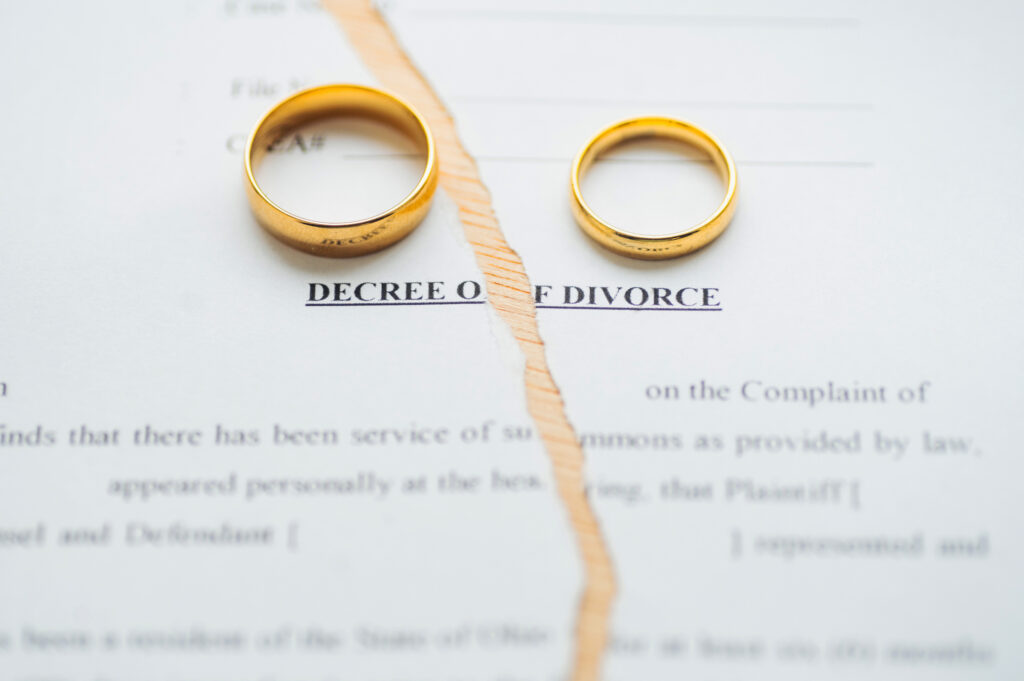 Divorce decree document with gold wedding rings and gavel on desk 