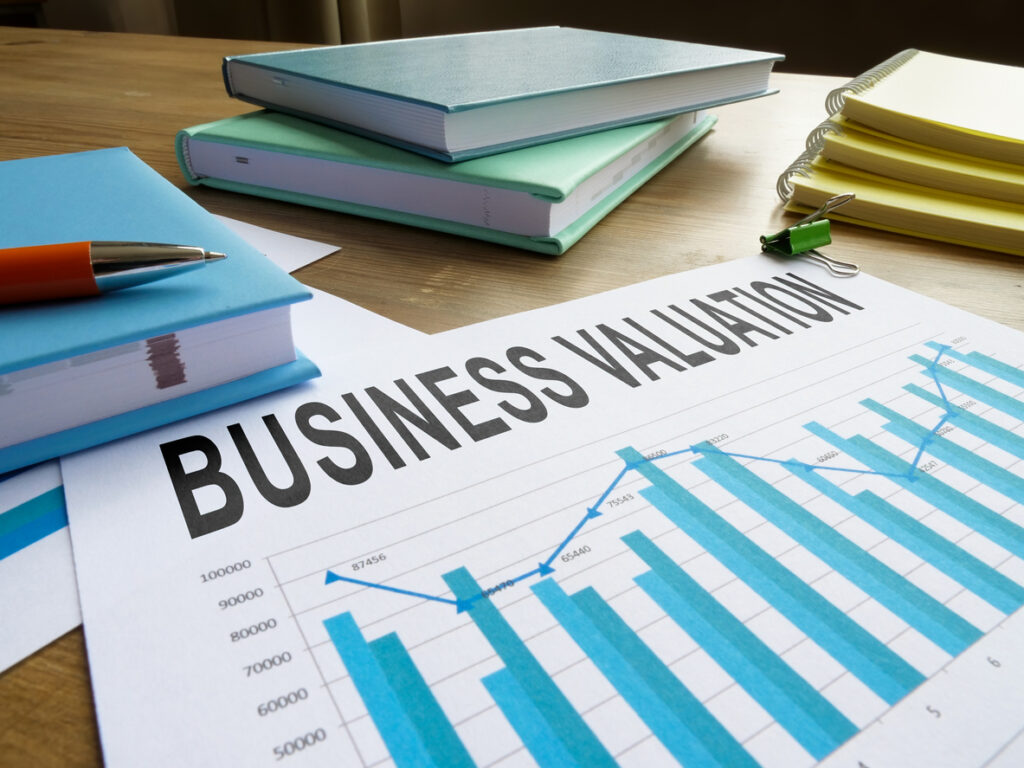 Business valuation document with books, notebooks, and red pen on desk