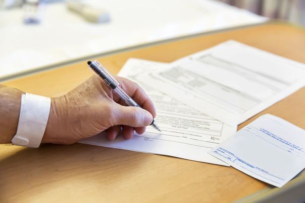 Close-up of a patient’s hand signing consent forms.
