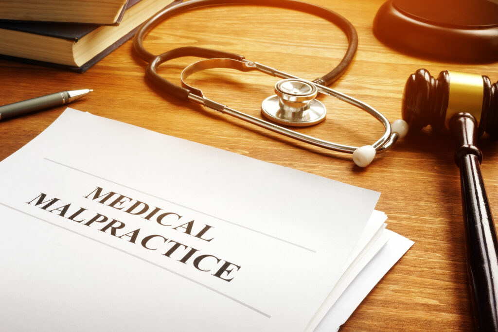 Medical malpractice document with pen, books, and gavel on desk