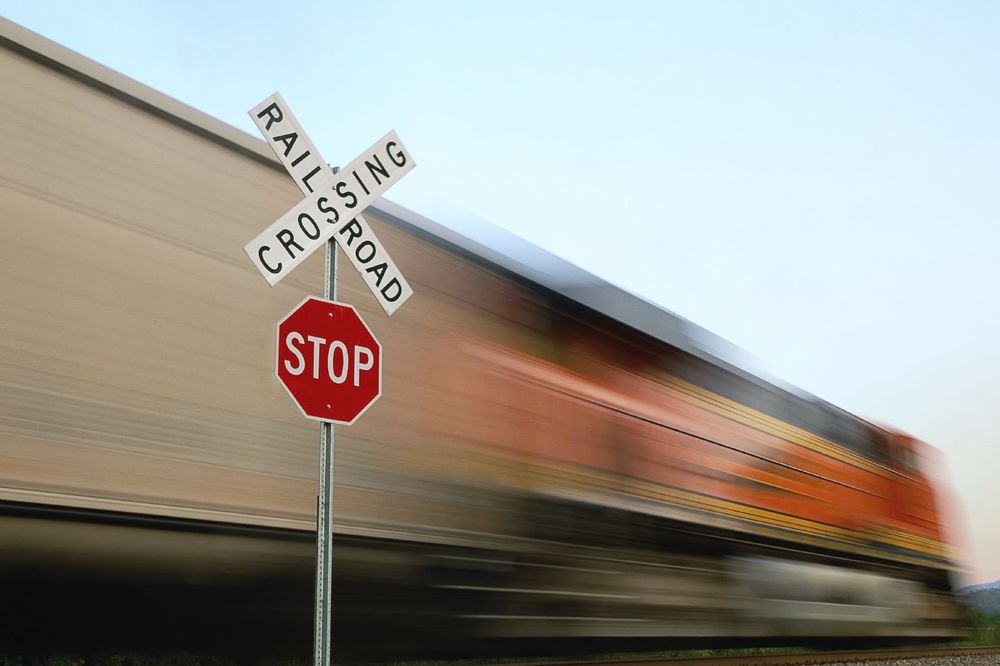Blurred image of a train speeding by railroad crossing sign.