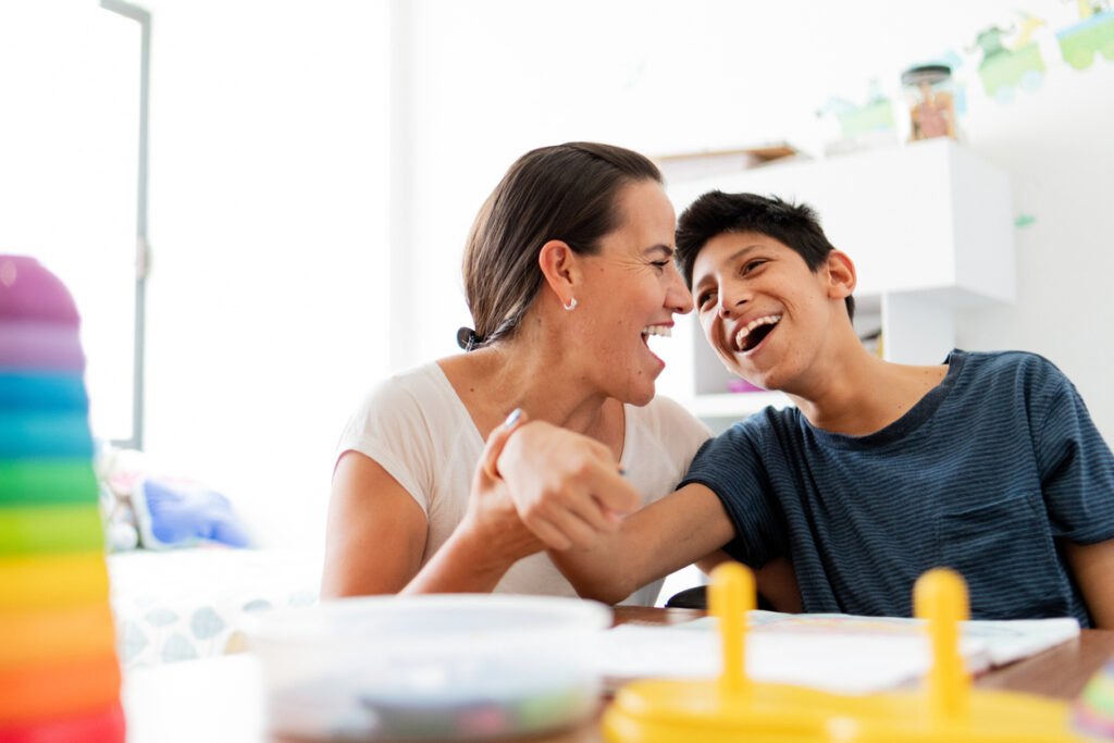 Smiling woman holding arm of boy with cerebral palsy