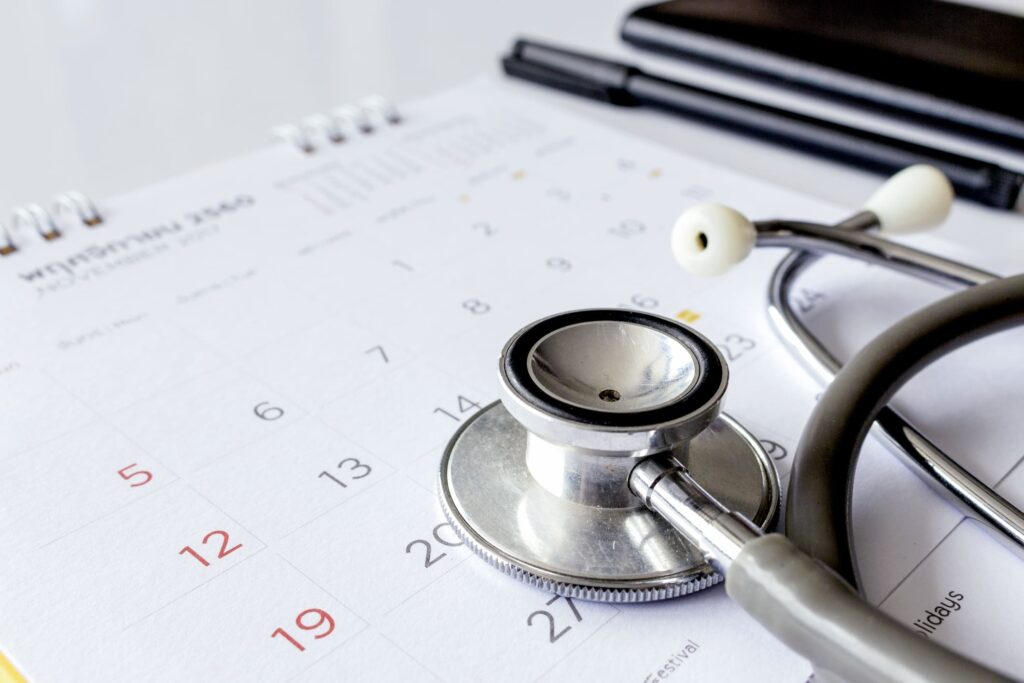 Close-up of stethoscope on calendar with pen and notebook in background